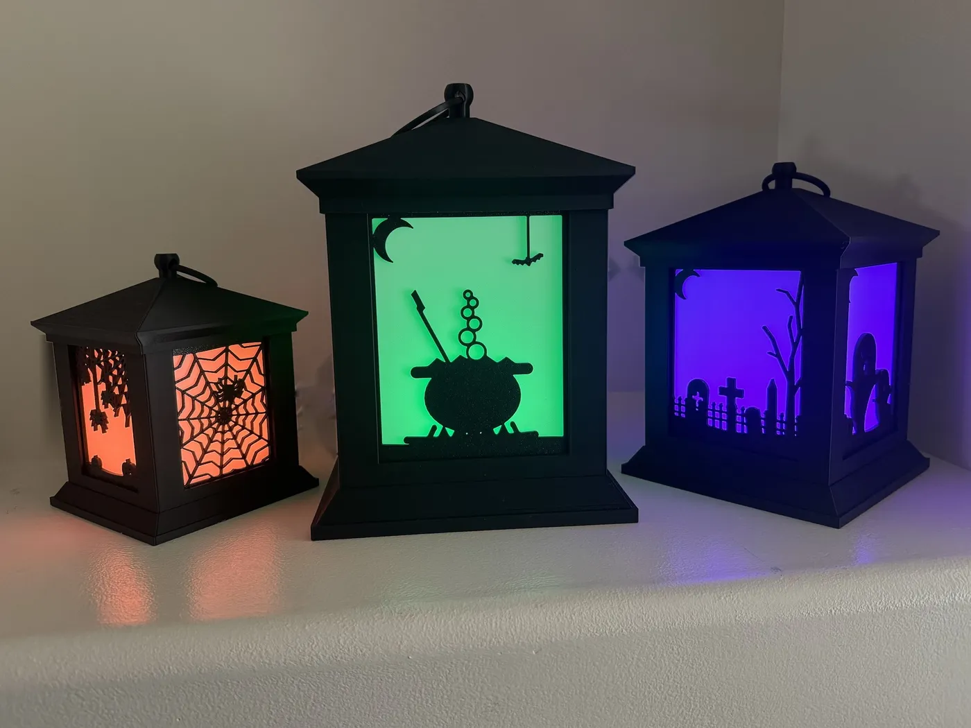 The same three lanterns glowing orange, green and purple